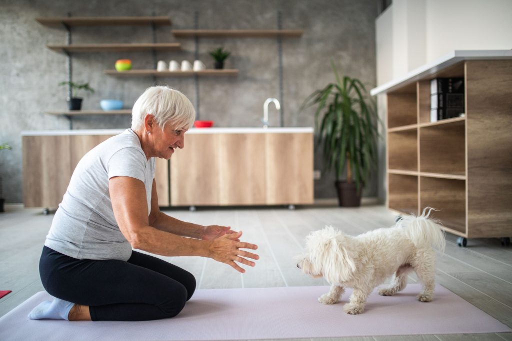 senior-woman-teaching-dog-yoga-on-a-yoga-mat-