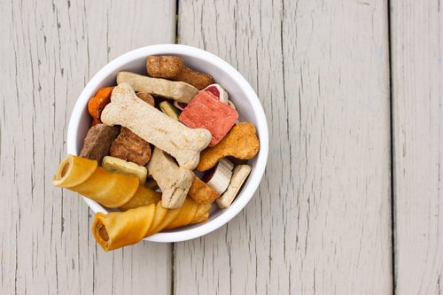 assortment of dog treats in a bowl with wooden background